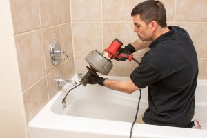 plumber-using-drain-snake-in-tub