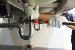 plumbers-hands-working-on-pipe-under-sink