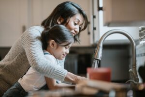 woman-and-girl-washing-hands-at-kitchen-sink