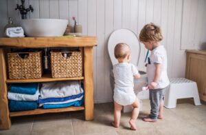 two-small-children-stand-in-toilet